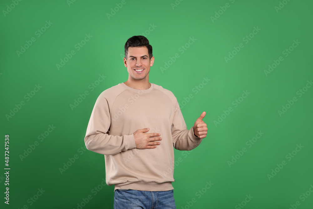 Happy healthy man touching his belly on green background Happy healthy man touching his belly on green background