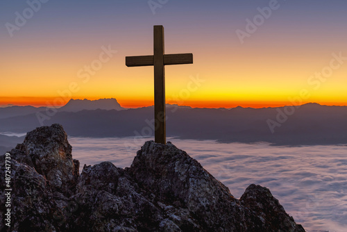 Silhouettes of crucifix symbol on top rock mist mountain with colorful sky background