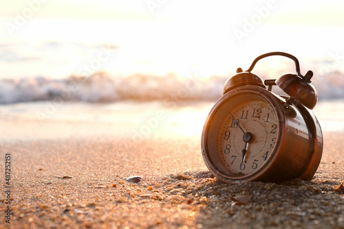 Morning of a new day, alarm clock on the beach sunlight in morning. Health concept.