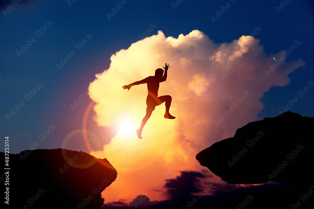 A silhouette man jump between 2021 and 2022 years with sunset background, Success new year concept.