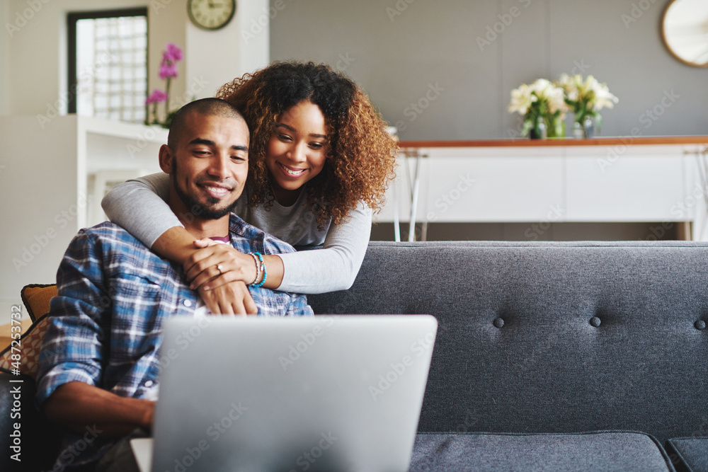 Thats the perfect movie for later. Cropped shot of an affectionate young couple sitting on the sofa together and using a laptop in their living room. Thats the perfect movie for later. Cropped shot of an affectionate young couple sitting on the sofa together and using a laptop in their living room.