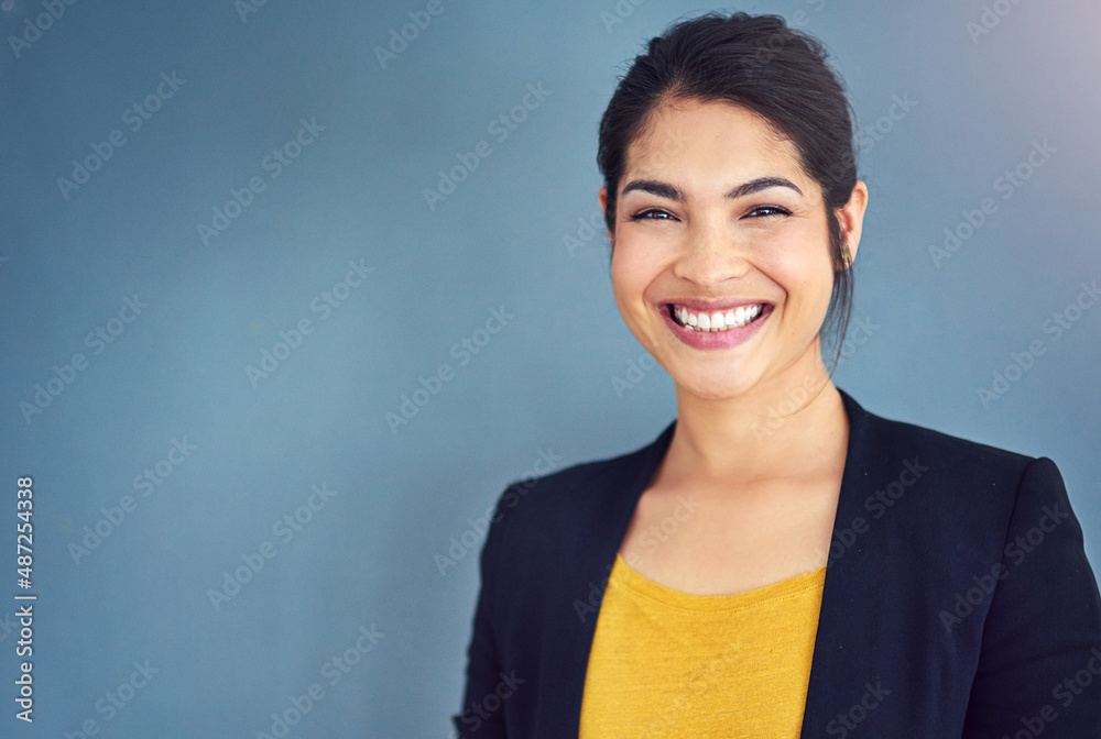 Confidence is the key to success. Studio portrait of an attractive young businesswoman standing against a blue background.