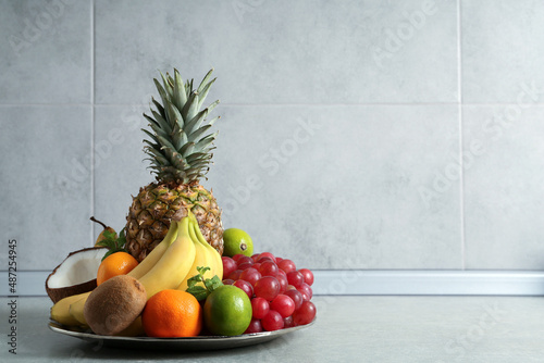 Fototapeta Naklejka Na Ścianę i Meble -  Plate with different ripe fruits on grey table. Space for text
