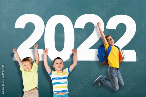 School children with drawing 2022 new year on the chalkboard.