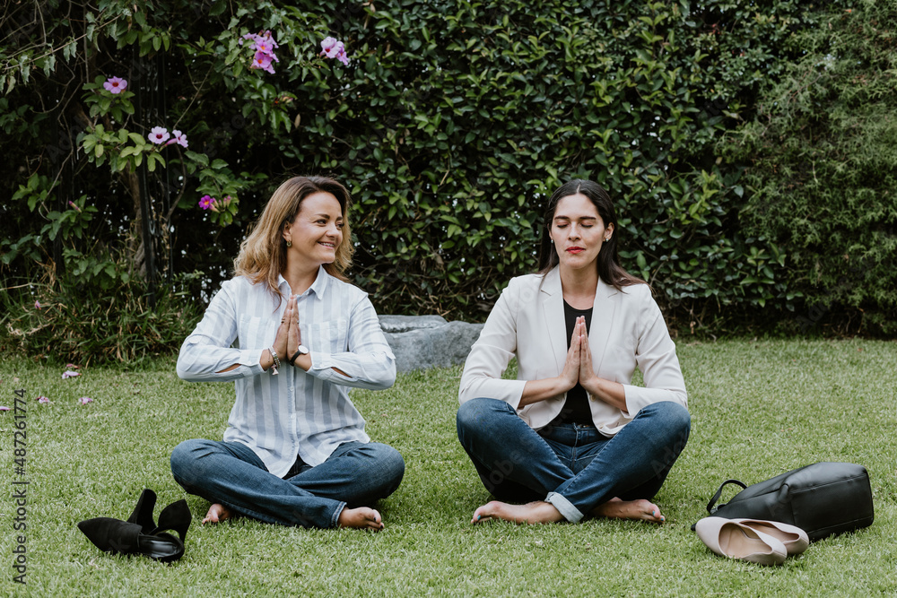 Latin business women sitting on grass and meditating at terrace office in Mexico Latin America	