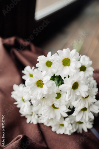 bouquet of white chrysanthemum flowers on a wooden dark window. spring mood. selective focus