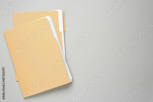 Yellow files with documents on light grey background, top view. Space for text photo