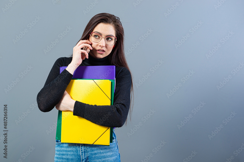 female with smartphone holding a colorfuls folders with documents, isolated on dark background female with smartphone holding a colorfuls folders with documents, isolated on dark background