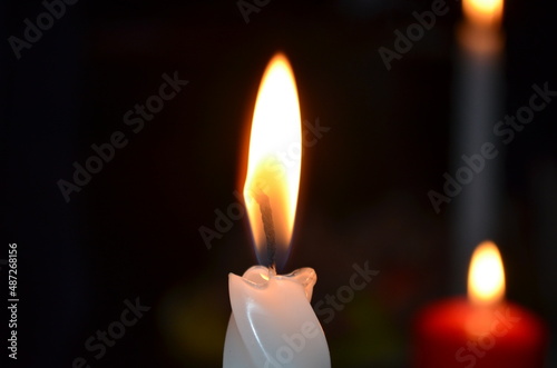 Lit white candle in the dark close up. High quality photo