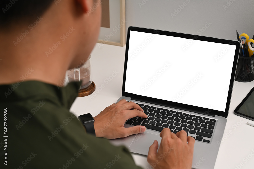 Over shoulder view young man using computer laptop on white table. Over shoulder view young man using computer laptop on white table.
