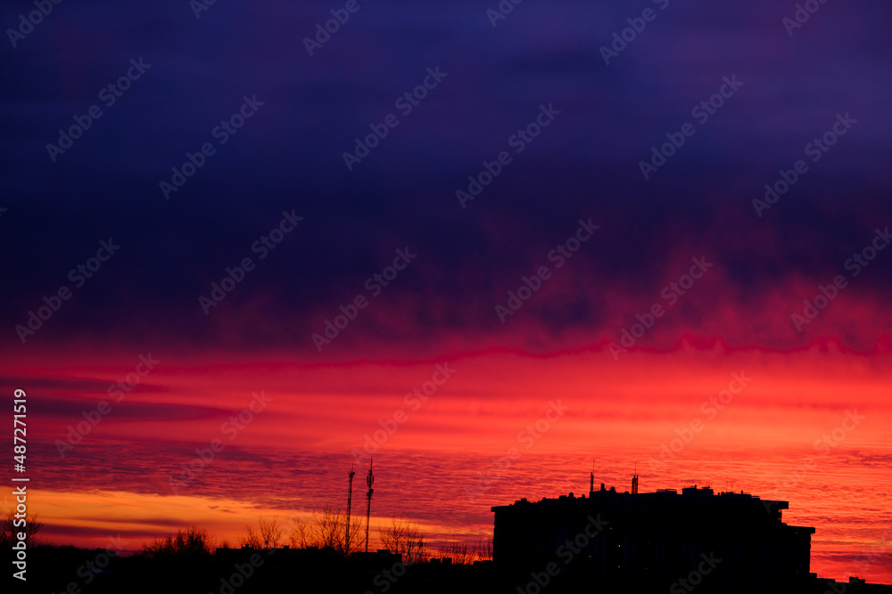 red sunset glow in the sky above the houses. scarlet evening sky.