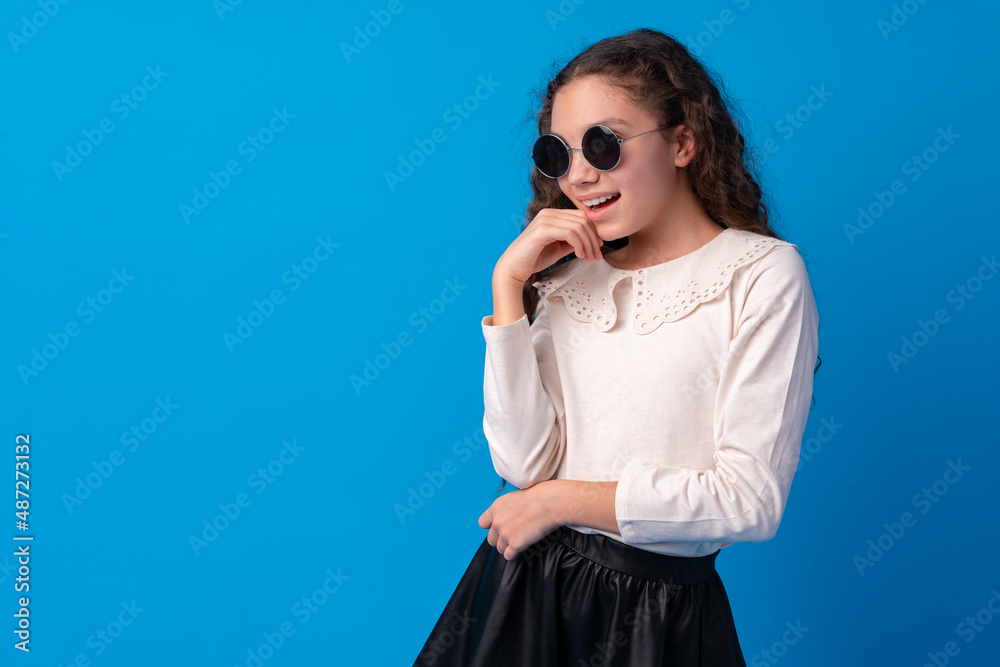 Little fashion girl in sunglasses against blue background Little fashion girl in sunglasses against blue background