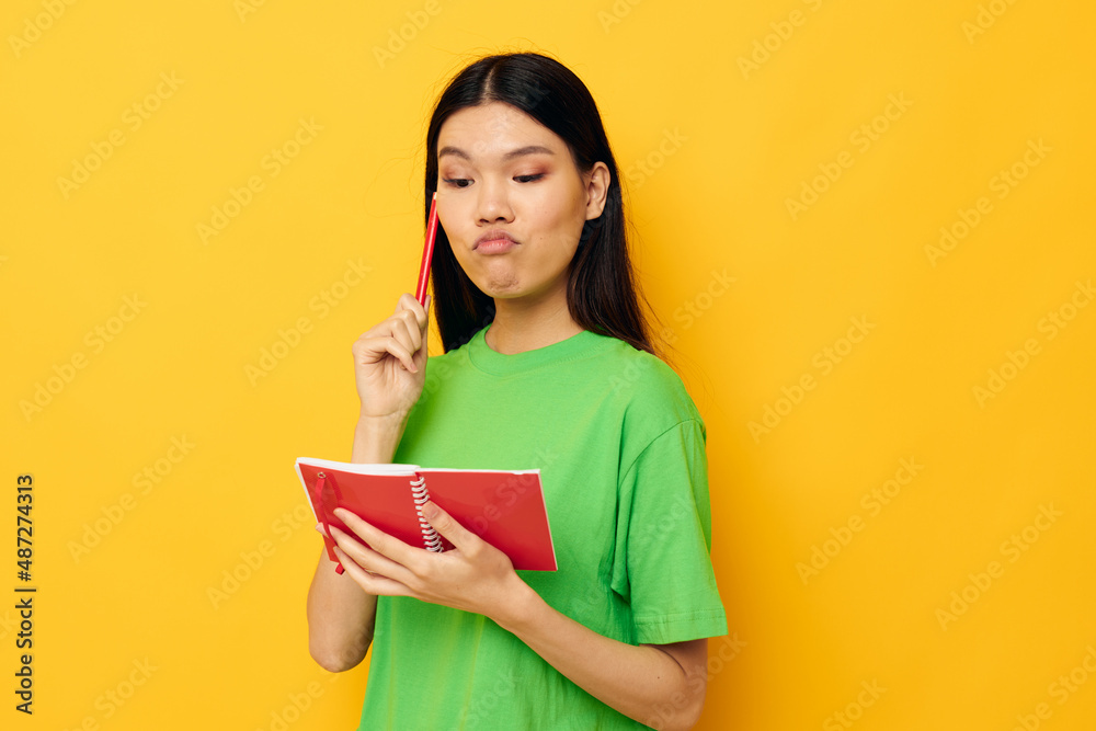 Charming young Asian woman green T-shirts with red notebook and pen isolated background unaltered Charming young Asian woman green T-shirts with red notebook and pen isolated background unaltered