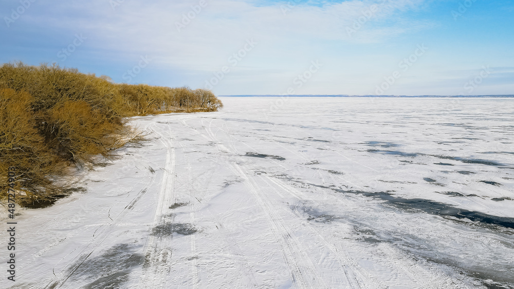 Vibrant shoreline with frozen lake with tracks