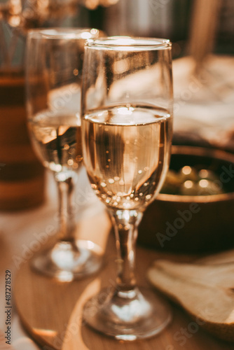 Two glasses of white wine on a wooden tray with fruits at sunset. © Olga