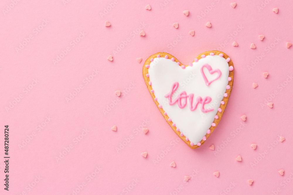 Valentine cookie with inscription LOVE on pink background. Sweet homemade present for loved one.