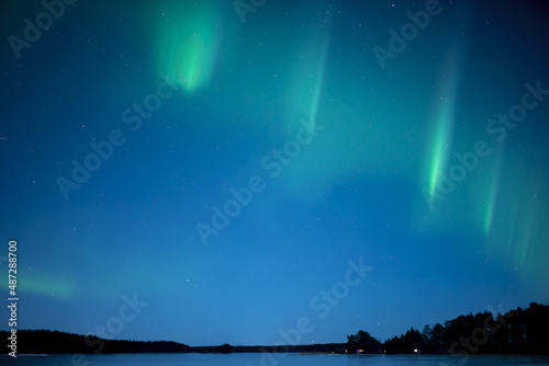 Northern lights dancing over frozen lake in Farnebofjarden national park in north of Sweden.
