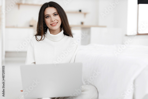 young cozy woman working in laptop at home indoor
