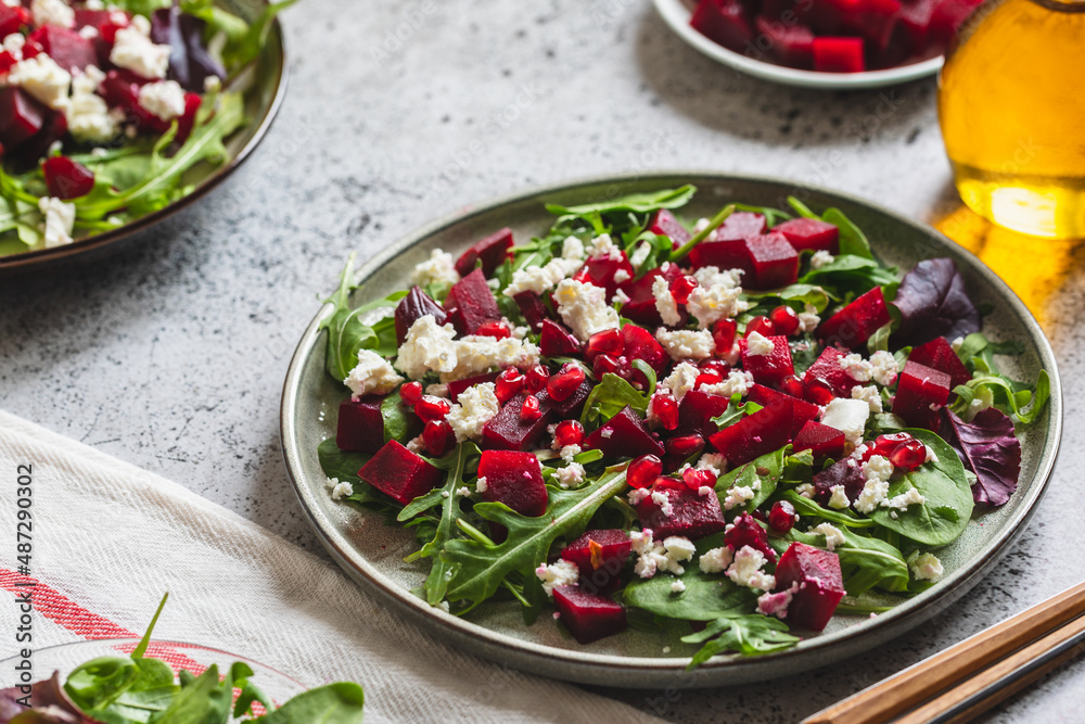 Arugula, Beet and cheese salad with pomegranate and dressing on plate on grey stone kitchen table background, place for text, top view Arugula, Beet and cheese salad with pomegranate and dressing on plate on grey stone kitchen table background, place for text, top view
