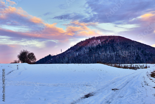 Early evening winter mountain landscape with beautiful blue sky and colorful clouds at dusk Path in the foreground leading to the hill. Natural background, wallpaper. Protected area Vrsatec, Slovakia.