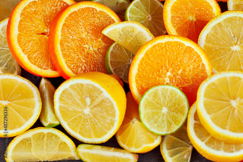 Oranges, lemons and limes cut into slices. Citrus vegetables on an orange background. Preparing vegetables for juice and cocktails.