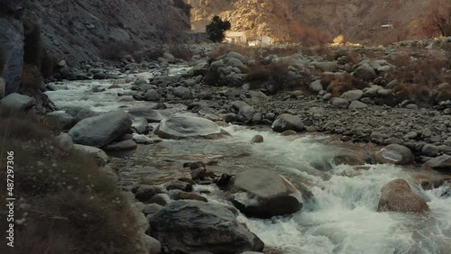 Panning shot of river water flowing through rocks in the mountains