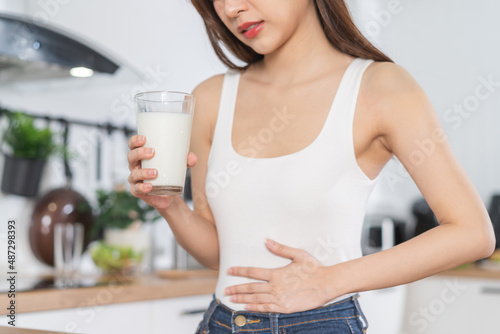 Pain, Allergy asian young woman, girl hand in belly suffer after drink glass of milk, unhappy and bad stomach ache. Lactose intolerance and dairy food , health problem concept. photo