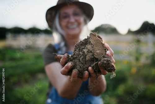 Close up of female famer hands holding soil outdoors at community farm. photo