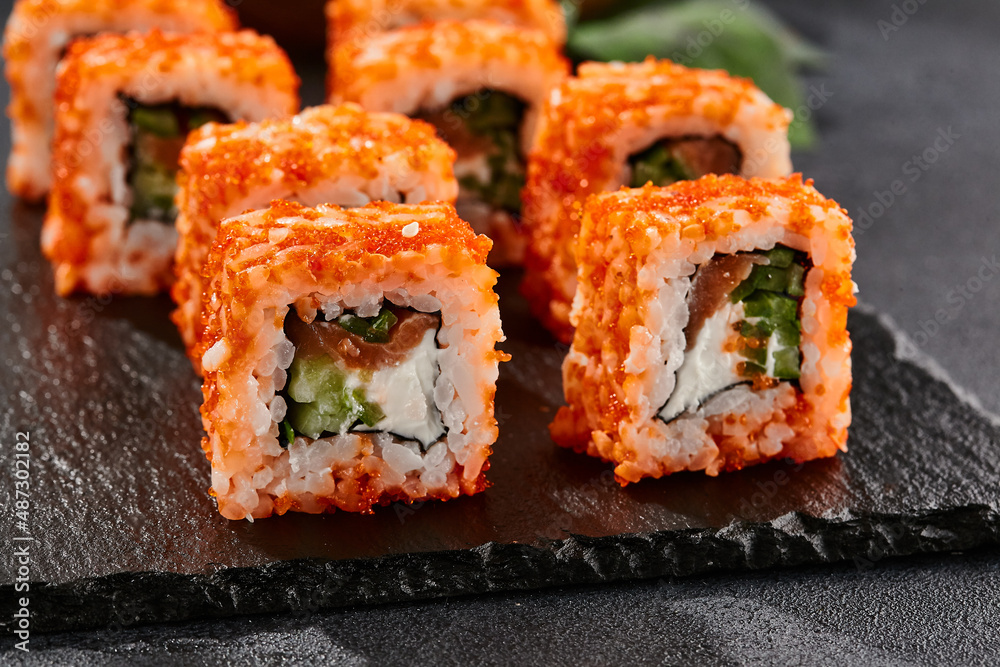 Maki sushi on dark slate. California maki with salmon. Sushi roll with