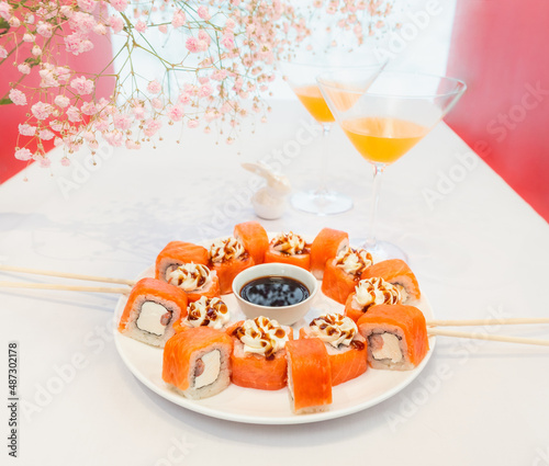 Sushi rolls food photo for menu. Laconic still life with the famous Japanese dish on a white and red background. Serving a romantic dinner together with flowers on the eve of spring
