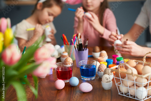Detail of caucasian family of four decorates easter eggs at home