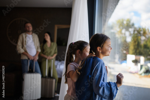 Happy young family with two children and luggage in room at luxury hotel, summer holiday.