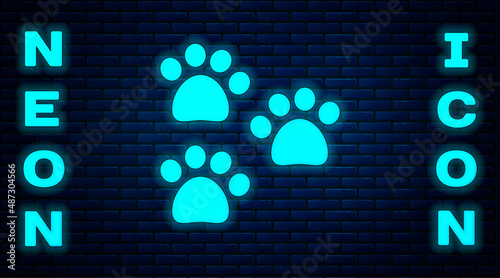 Glowing neon Paw print icon isolated on brick wall background. Dog or cat paw print. Animal track. Vector
