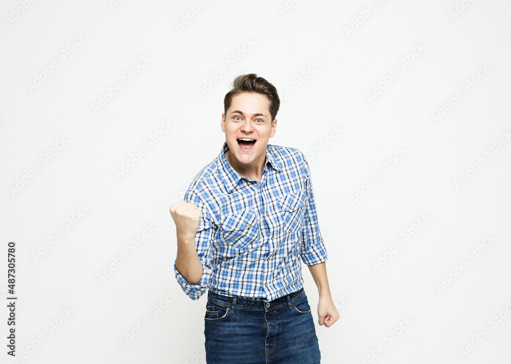Fototapeta premium Portrait of a young cheerful excited man wearing blue plaid shirt. celebrating success