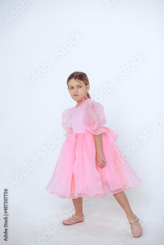 A beautiful cheerful little girl about 7 years old in a beautiful dress on an isolated white background.A place for your text.