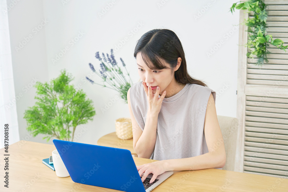女性　パソコンを見て驚く　リビング