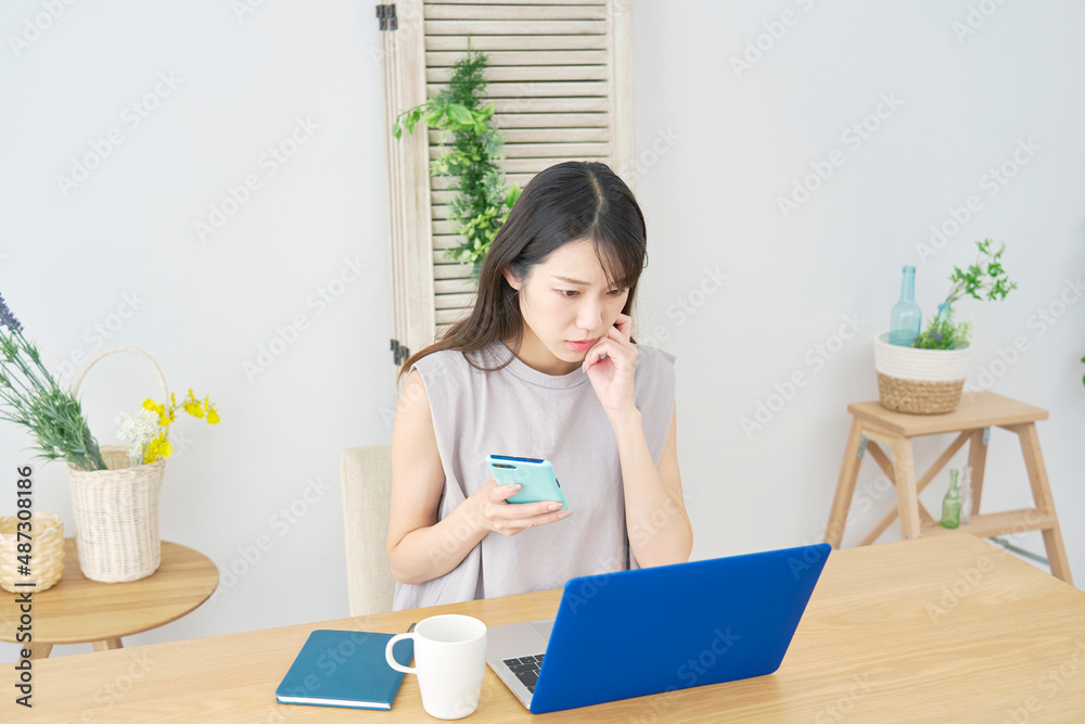 女性　パソコンを見て悩む　リビング
