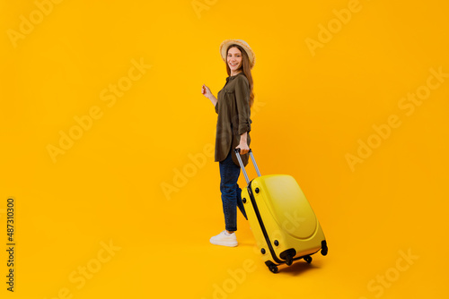 Tourist Lady Standing With Suitcase Posing Over Yellow Studio Background