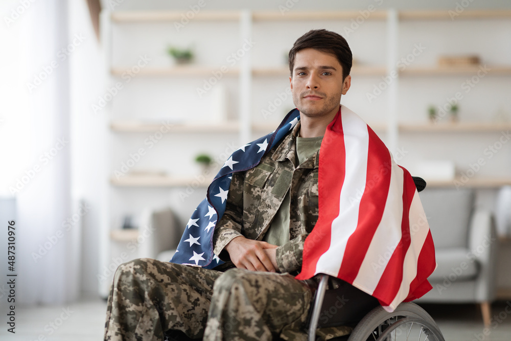 Handsome military guy in wheelchair with flag of the US - obrazy, fototapety, plakaty 