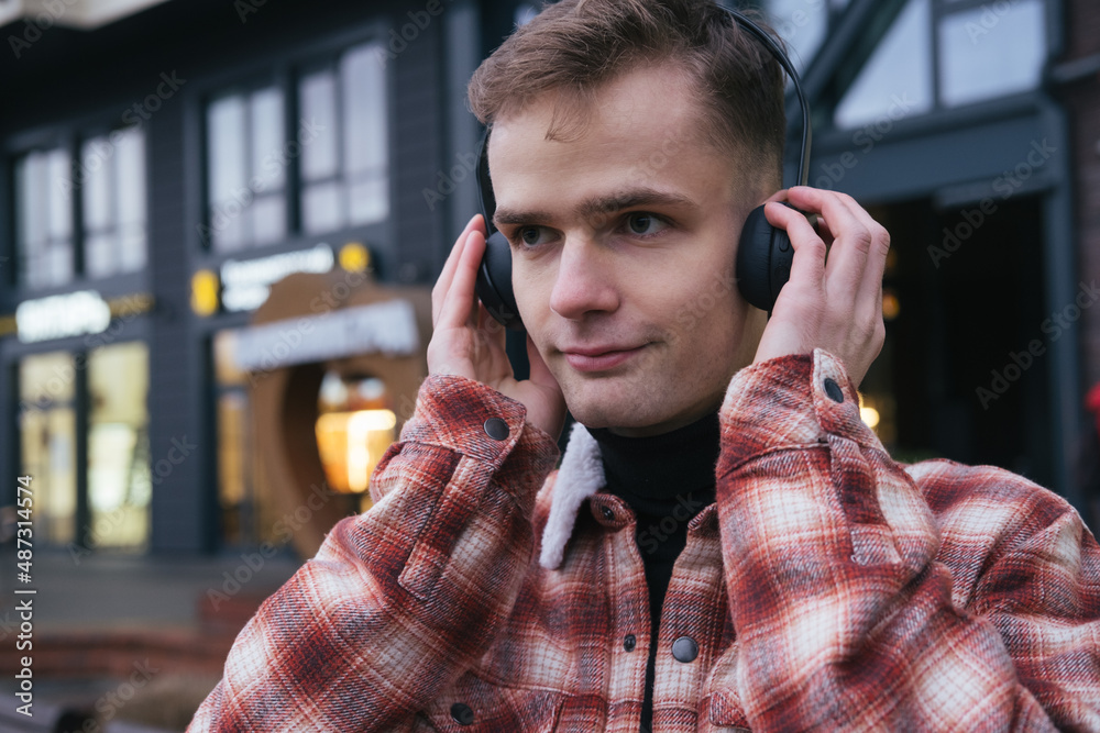 happy smiling positive guy listening to music on the street with headphones