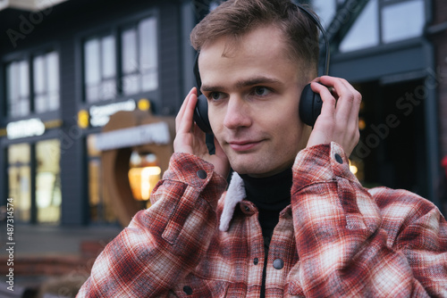 Obraz na płótnie happy smiling positive guy listening to music on the street with headphones w salonie