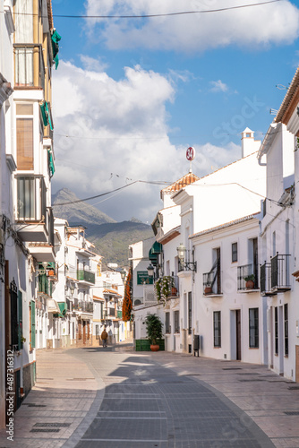 Beautiful streets of Nerja. Typically Andalusian houses. Small streets with white houses and flower pots in balcony. Touristic travel destination on Costa del Sola - Malaga. Sunny winter days