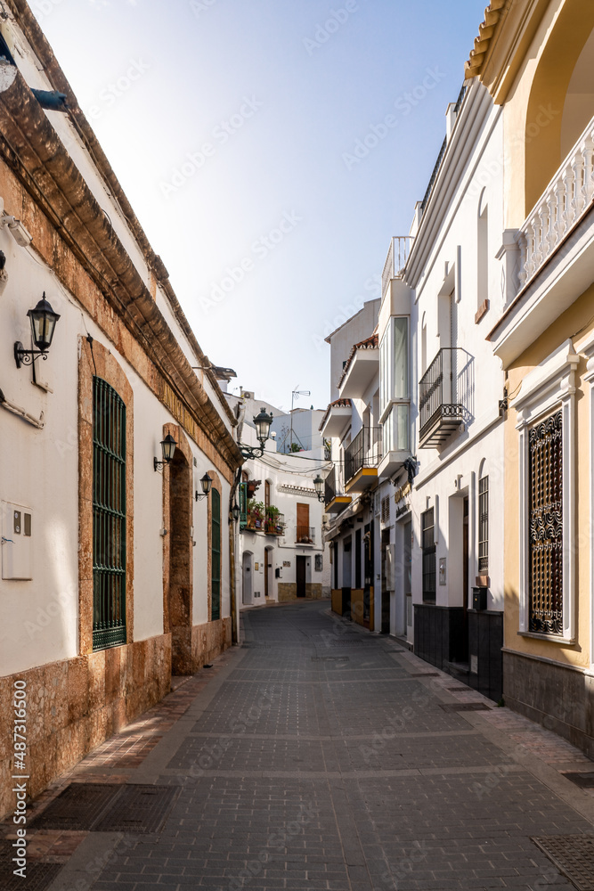 Beautiful streets of Nerja. Typically Andalusian houses. Small streets with white houses and flower pots in balcony. Touristic travel destination.