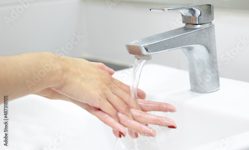 Washing hands. Covid-19 Coronavirus pandemic prevention. Hygiene concept. A woman washing hands in bathroom.