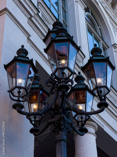 Close-up of the upper part of a historic street lantern of black cast iron in front of the munich theatre, Munich Germany © Enrico Buss