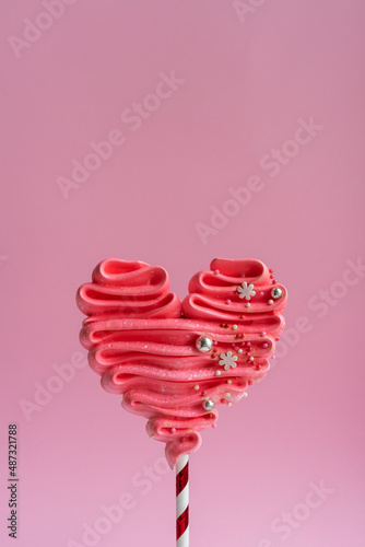 Pink meringue heart on a stick. Pink background, sweets for lovers. Meringue handmade.