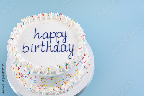 white cake with the inscription happy birthday on blue background, top view