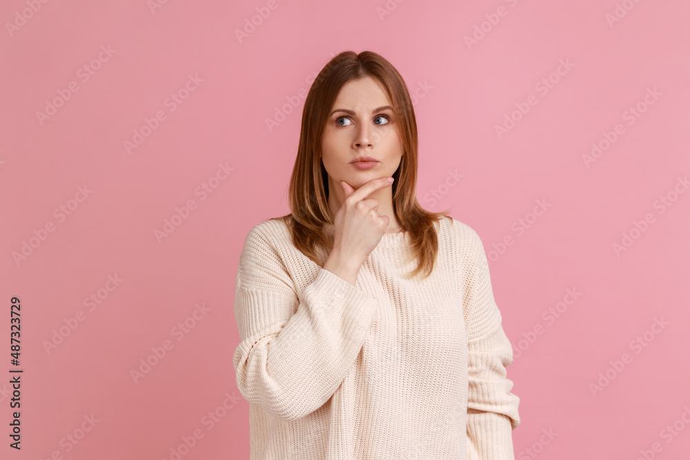 Portrait of blond woman standing deep in thoughts with puzzled serious doubtful face expression, making difficult decision, wearing white sweater. Indoor studio shot isolated on pink background. Portrait of blond woman standing deep in thoughts with puzzled serious doubtful face expression, making difficult decision, wearing white sweater. Indoor studio shot isolated on pink background.