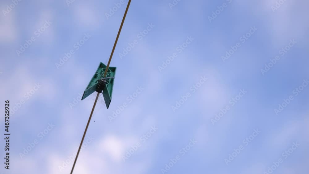 Plastic Clothespin On A Clothesline Against Cloudy Sky. low angle Plastic Clothespin On A Clothesline Against Cloudy Sky. low angle