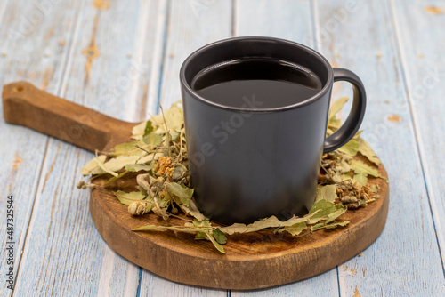 Winter herbal tea on a blue wood background. Winter tea. immune-boosting herbal tea. Medicinal tea prepared from linden leaves, Clove particles and Chamomile © enezselvi